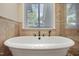 Close up of a soaking tub with a faucet and hardware in a tile bathroom with a window view at 217 Dalmeny Dr, Cary, NC 27513