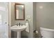 Elegant powder room featuring a pedestal sink, decorative mirror, and neutral wall color at 217 Dalmeny Dr, Cary, NC 27513
