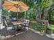 Relaxing back deck with patio set, umbrella, and a view of the lush, green backyard at 221 Antique Lace Way, Holly Springs, NC 27540