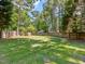 Large backyard enclosed by a wooden fence and bordered by mature trees at 221 Antique Lace Way, Holly Springs, NC 27540