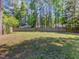 View of a spacious backyard, surrounded by trees and a wood fence at 221 Antique Lace Way, Holly Springs, NC 27540