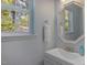 Powder room with a white vanity, decorative mirror and natural light from the window at 221 Antique Lace Way, Holly Springs, NC 27540
