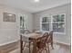 Inviting dining room featuring natural light, hardwood floors, and classic wood table set for four at 221 Antique Lace Way, Holly Springs, NC 27540