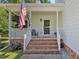 Inviting front porch with a comfortable chair, ideal for enjoying the neighborhood views at 221 Antique Lace Way, Holly Springs, NC 27540