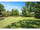 Large grassy backyard with mature trees and a partial wooden fence at 2644 Bloomsberry Ridge Dr, Fuquay Varina, NC 27526