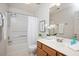 Bright bathroom featuring a tub with shower, vanity with mirror and white floral accents at 2644 Bloomsberry Ridge Dr, Fuquay Varina, NC 27526