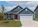 Charming single-story home with blue siding, a two-car garage, manicured lawn and bright red front door at 265 Purple Aster St, Youngsville, NC 27596