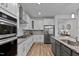 Modern kitchen features white cabinets, granite countertops, stainless steel appliances, and wood floors at 265 Purple Aster St, Youngsville, NC 27596