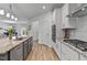 Open kitchen features white cabinets, granite countertops, stainless steel appliances, and wood floors at 265 Purple Aster St, Youngsville, NC 27596
