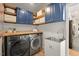 Laundry room with blue cabinets, wood counters, stainless steel washer/dryer, and utility sink at 3 Waconda Ct, Durham, NC 27713