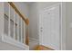 Carpeted staircase with oak banister and white front door to the home at 400 Nottinghill Walk, Apex, NC 27502