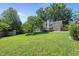 Spacious backyard with a lush green lawn, mature trees, a wooden fence, a shed, and a back deck at 405 E Millbrook Rd, Raleigh, NC 27609