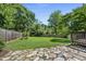 Expansive backyard featuring a stone patio, lush green grass, mature trees, and a wooden privacy fence at 405 E Millbrook Rd, Raleigh, NC 27609