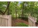 View into a backyard surrounded by a white fence and dense trees, offering privacy and tranquility at 409 Englewood Dr, Chapel Hill, NC 27514