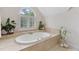 Bright bathroom features an oval tub under a window with white shutters and stylish plants at 409 Englewood Dr, Chapel Hill, NC 27514