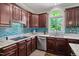 Charming kitchen features cherry cabinets, granite countertops, a stylish backsplash, and a sunny arched window at 409 Englewood Dr, Chapel Hill, NC 27514