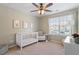 Bedroom with a white crib, chair, and bright window with blinds, creating a cozy atmosphere at 4533 Pale Moss Dr, Raleigh, NC 27606