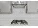 Close-up of a modern stovetop with stainless steel range hood and white subway tile backsplash at 4716 Crescent Square St # 1314, Raleigh, NC 27616