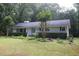 Charming single-story home with a lush green lawn, mature trees, and a lovely blue front door at 5112 Stephens Ln, Durham, NC 27712