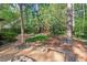 Tranquil backyard with a stone fire pit, bench seating, and mature trees for privacy at 5315 Mccormick Rd, Durham, NC 27713