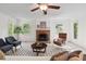 Well-lit living room featuring a brick fireplace, ceiling fan, and comfortable seating area at 5315 Mccormick Rd, Durham, NC 27713