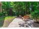 A serene backyard features a charming patio, surrounded by lush trees, and outdoor furniture, perfect for relaxation at 553 Lake Gaston Dr, Fuquay Varina, NC 27526