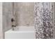 Close-up of a bathtub with a neutral tile surround and a patterned shower curtain, adding a decorative touch at 553 Lake Gaston Dr, Fuquay Varina, NC 27526