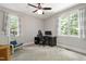 Neutral bedroom with light gray walls, a ceiling fan, two windows, and a small desk area at 553 Lake Gaston Dr, Fuquay Varina, NC 27526
