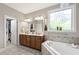 Bright bathroom features a double vanity, soaking tub with decorative window, and walk-in closet at 553 Lake Gaston Dr, Fuquay Varina, NC 27526
