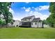 View of the home's backyard and lawn, showcasing the house with a screened-in porch in a serene, tree-lined neighborhood at 74 Fountain Dr, Clayton, NC 27520