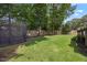 Backyard with green grass, a trampoline, and mature trees with a wooden fence at 7917 Rooksley Ct, Raleigh, NC 27615