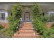 Inviting front porch with brick steps, lush greenery, and decorative lanterns at 7917 Rooksley Ct, Raleigh, NC 27615