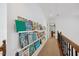 Hallway with custom bookshelves, railing and neutral carpet in well lit setting at 7917 Rooksley Ct, Raleigh, NC 27615