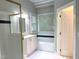 Bright bathroom featuring a shower with gold trim, vanity, soaking tub and white tile at 8100 Laurel Mountain Rd, Raleigh, NC 27613