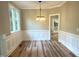 Cozy dining area with wainscoting, wood-look floors, and modern lighting, flowing into an adjacent living space at 8100 Laurel Mountain Rd, Raleigh, NC 27613