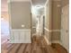 Hallway with white wainscoting, neutral walls, wood-look flooring, and doors leading to various rooms of the home at 8100 Laurel Mountain Rd, Raleigh, NC 27613