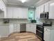 Well-lit kitchen with white cabinets, stainless steel appliances, and attractive light wood flooring at 8100 Laurel Mountain Rd, Raleigh, NC 27613