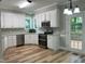 Well-lit kitchen with white cabinets, stainless steel appliances, and attractive light wood flooring at 8100 Laurel Mountain Rd, Raleigh, NC 27613