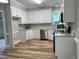 Well-lit kitchen with white cabinets, stainless steel appliances, and attractive light wood flooring at 8100 Laurel Mountain Rd, Raleigh, NC 27613