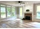 Bright living room with fireplace, ceiling fan, large windows and attractive light wood flooring at 8100 Laurel Mountain Rd, Raleigh, NC 27613