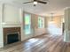 Inviting living room with a classic brick fireplace, large windows, elegant molding, and modern wood-look floors at 8100 Laurel Mountain Rd, Raleigh, NC 27613