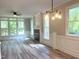 Bright and airy living room with a brick fireplace, large windows, elegant wainscoting, and stylish light fixture at 8100 Laurel Mountain Rd, Raleigh, NC 27613