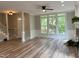 Open living room with staircase, brick fireplace, large windows and attractive light wood flooring at 8100 Laurel Mountain Rd, Raleigh, NC 27613