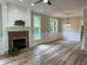 Open living room with brick fireplace, large windows, attractive light wood flooring, and decorative trim at 8100 Laurel Mountain Rd, Raleigh, NC 27613