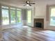 Spacious living room with brick fireplace, ample natural light from large windows, and modern wood-look floors at 8100 Laurel Mountain Rd, Raleigh, NC 27613