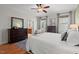 Bright bedroom with hardwood floors, a ceiling fan, and a large dresser with mirror at 997 Windy Rd, Apex, NC 27502