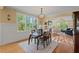 Bright dining area with large windows, hardwood floors, and an elegant chandelier leading to the living room at 997 Windy Rd, Apex, NC 27502