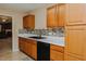 Kitchen featuring oak cabinets, tile backsplash, white countertops, and a black dishwasher at 101 Kingston Ln, Graham, NC 27253
