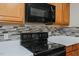 Close-up of a black electric stovetop with overhead microwave and wooden cabinetry at 101 Kingston Ln, Graham, NC 27253