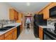 View of kitchen with wooden cabinets, black appliances, and a breakfast nook at 101 Kingston Ln, Graham, NC 27253
